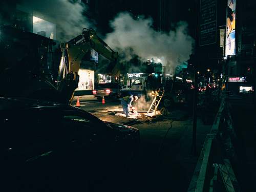 united states construction workers and vehicles on road during nighttime urban